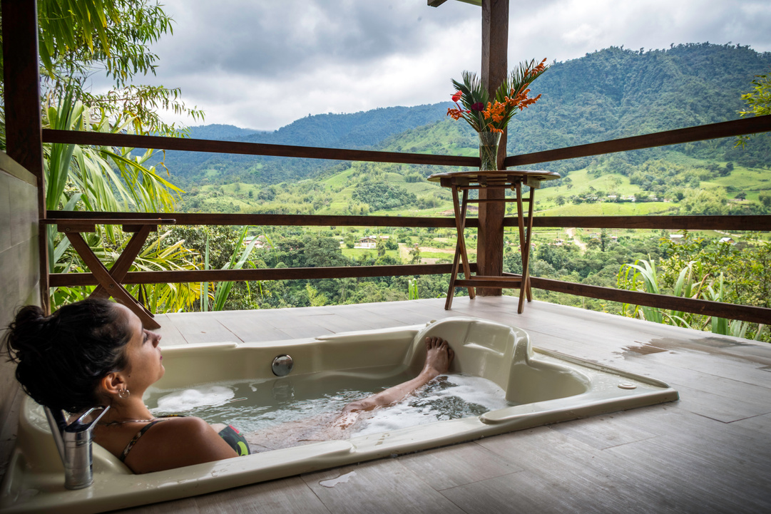 Woman Inside Bathtub on Hotel Balcony with Mountain View